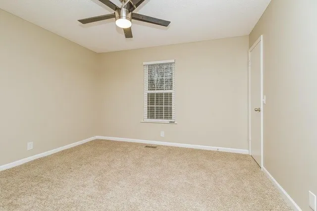 an empty room with a window and a fan