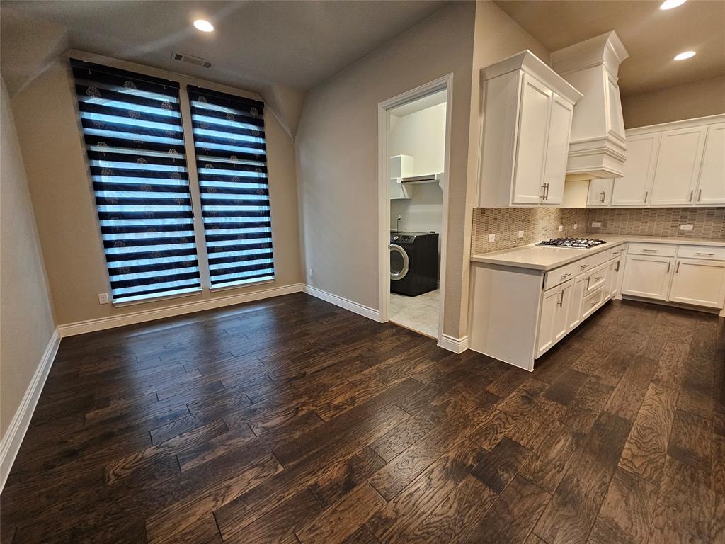2065 Snapdragon Road Frisco, TX 75033 - Photo 12 of 39 Spacious kitchen area featuring warm wood-finish flooring, white cabinetry, a natural stone countertop, and a tiled backsplash