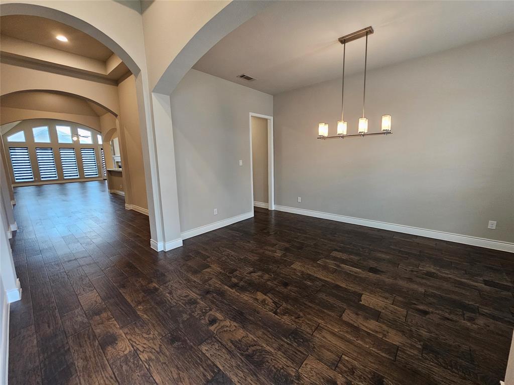 2065 Snapdragon Road Frisco, TX 75033 - Photo 14 of 39 Spacious room featuring rich wood-finish flooring and a contemporary linear chandelier