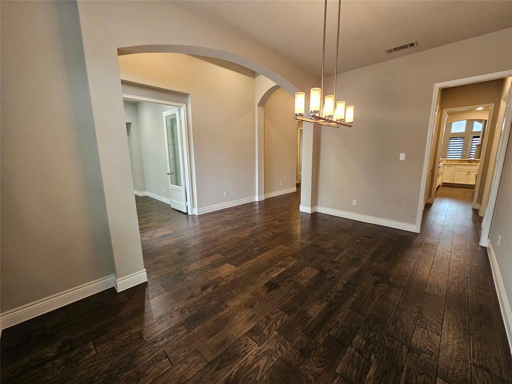 2065 Snapdragon Road Frisco, TX 75033 - Photo 15 of 39 Spacious room featuring wood-finish flooring, an arched doorway, and a contemporary linear chandelier with cylindrical shades