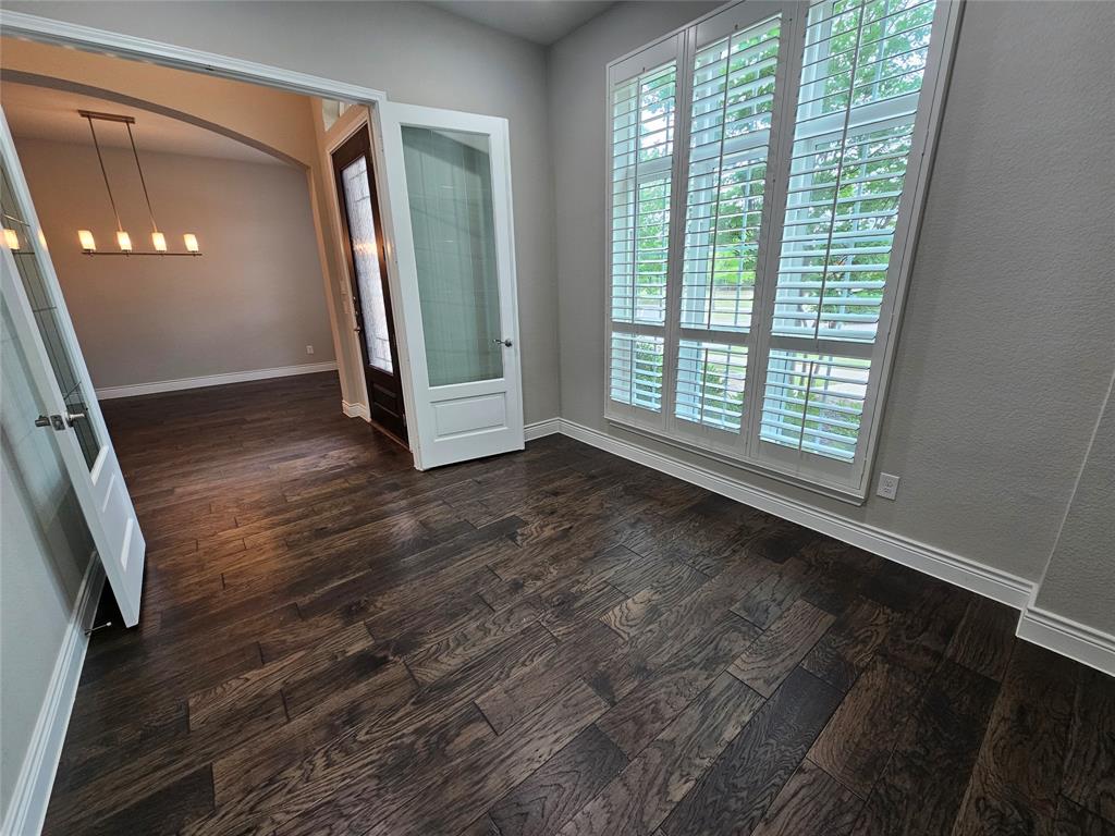 2065 Snapdragon Road Frisco, TX 75033 - Photo 17 of 39 Hardwood-finish flooring throughout, featuring a large window with plantation shutters, French doors with frosted glass panels, and an arched entry