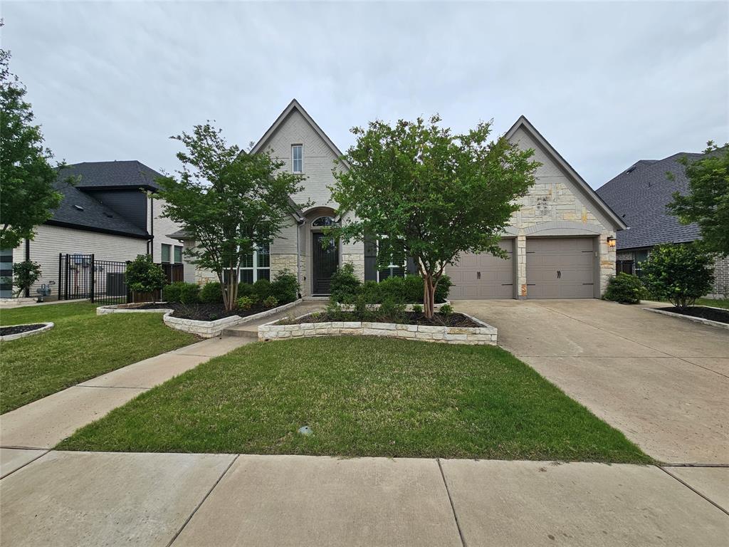2065 Snapdragon Road Frisco, TX 75033 - Photo 2 of 39 Stone and brick facade home featuring a two-car garage, arched entry, and manicured landscaping with stone-lined beds