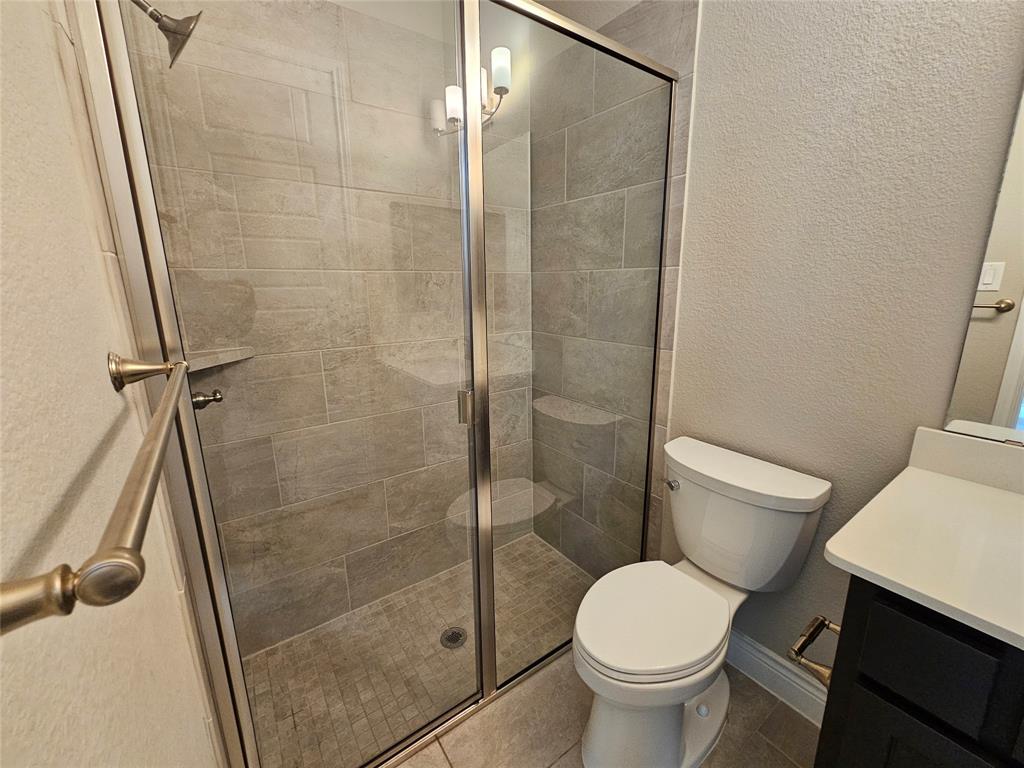 2065 Snapdragon Road Frisco, TX 75033 - Photo 25 of 39 Walk-in shower with clear glass enclosure and light gray tile surround, featuring a built-in shower bench and shower niche