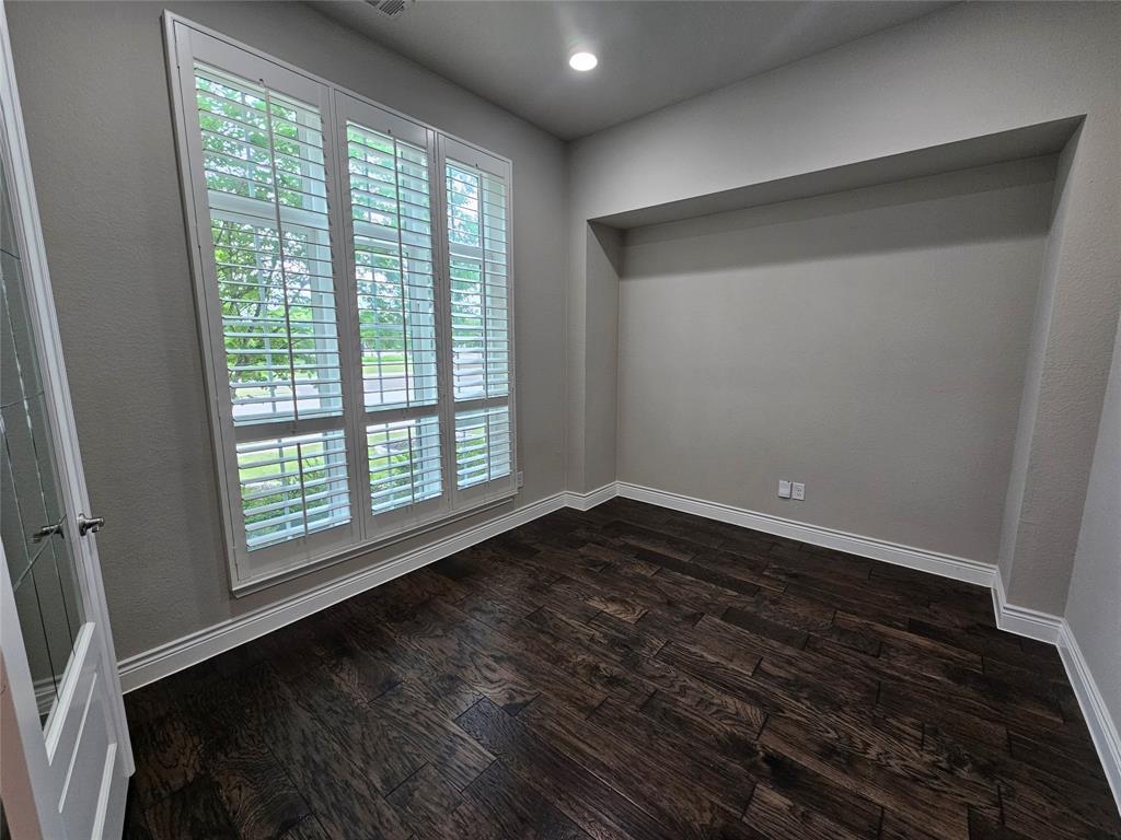 2065 Snapdragon Road Frisco, TX 75033 - Photo 26 of 39 Room featuring wood-finish flooring, a prominent window with plantation shutters, a recessed wall niche, and a ceiling-mounted recessed light fixture
