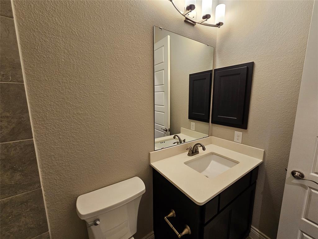 2065 Snapdragon Road Frisco, TX 75033 - Photo 32 of 39 Bathroom featuring a dark wood-finish vanity with a light countertop, an undermount sink, a rectangular mirror, and a three-bulb light fixture