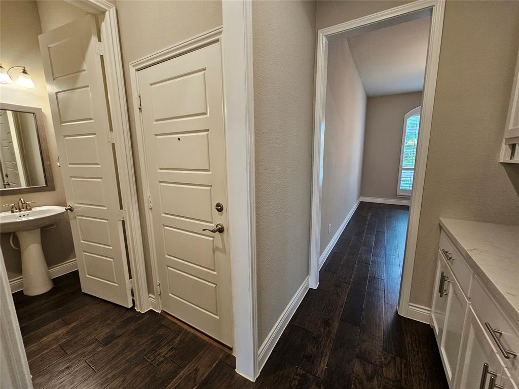 2065 Snapdragon Road Frisco, TX 75033 - Photo 33 of 39 Hallway featuring wood-finish flooring, white paneled doors, and a built-in vanity with a light-toned countertop