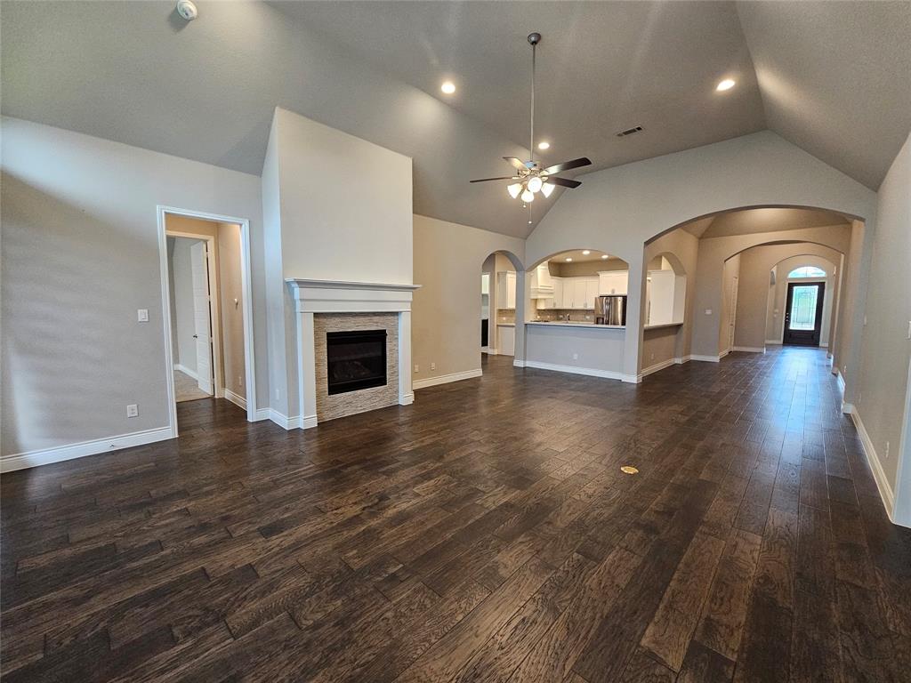 2065 Snapdragon Road Frisco, TX 75033 - Photo 9 of 39 Vaulted ceiling living area featuring dark wood-finish flooring, a fireplace with a stone tile surround and white mantel, and recessed lighting