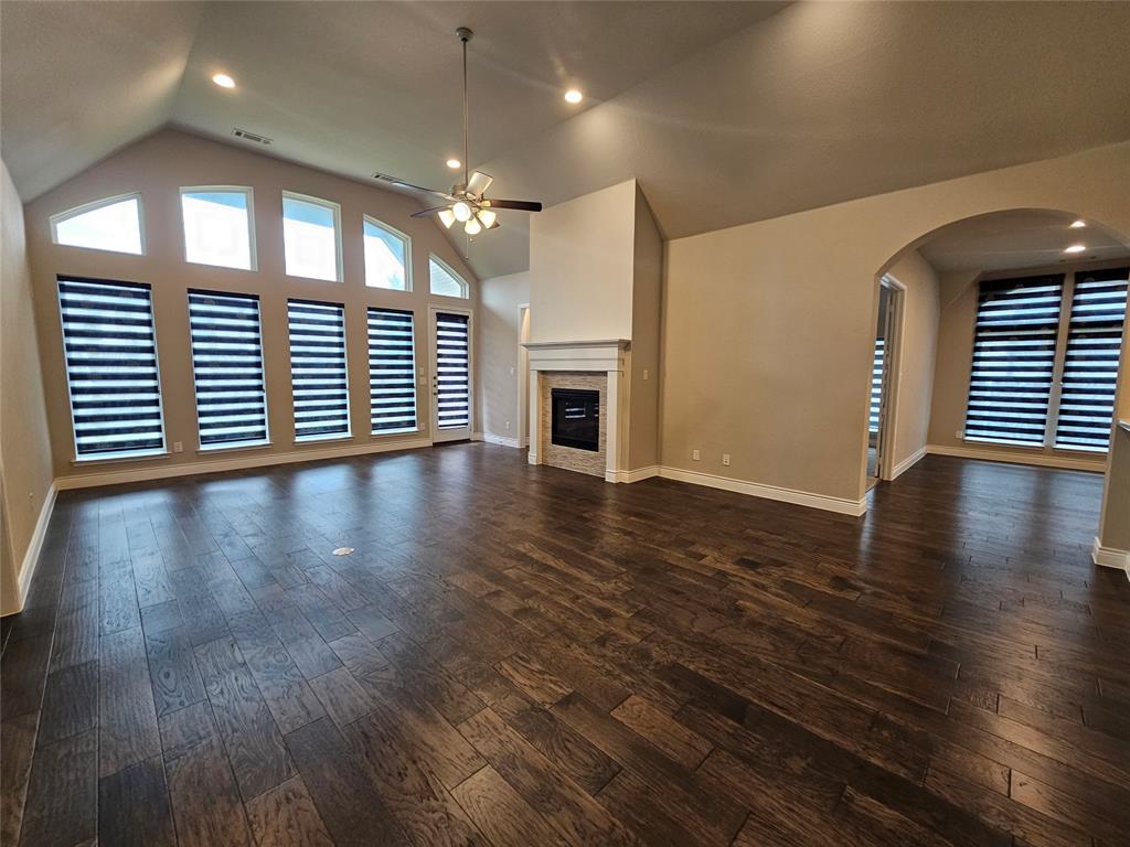 2065 Snapdragon Road Frisco, TX 75033 - Photo 10 of 39 Spacious room featuring vaulted ceilings, wood-finish flooring, a fireplace with a stone surround, recessed lighting, and large windows with blinds