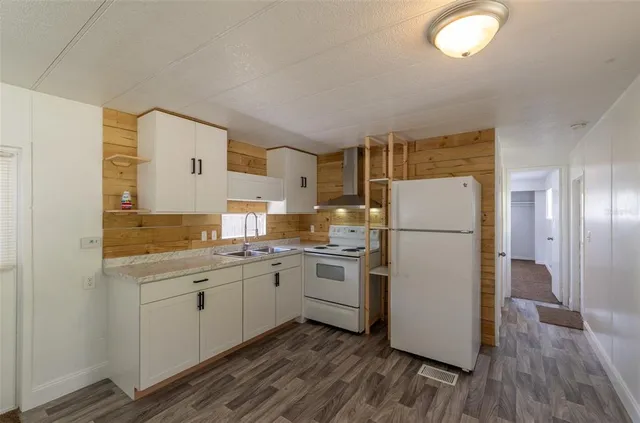 a kitchen with a refrigerator a sink and wooden floor