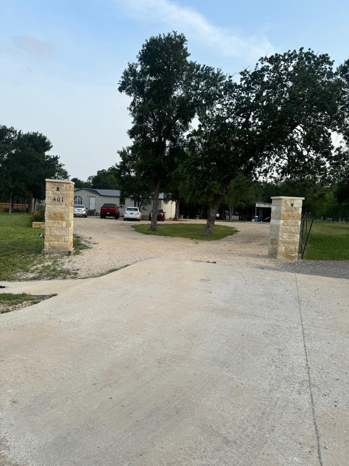 Stone entry columns frame the property entrance, leading to a gravel driveway