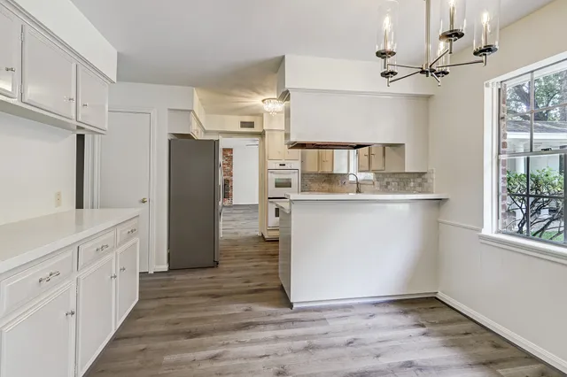 a kitchen with stainless steel appliances granite countertop a refrigerator a sink dishwasher and white cabinets with wooden floor