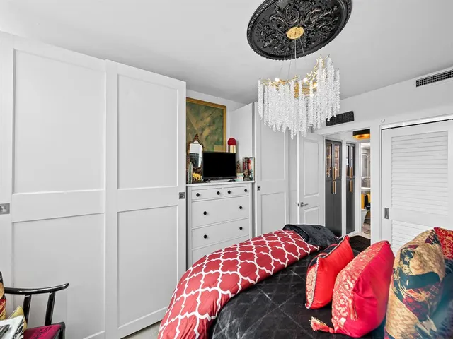 a bedroom with a bed and a flat tv screen on the dresser