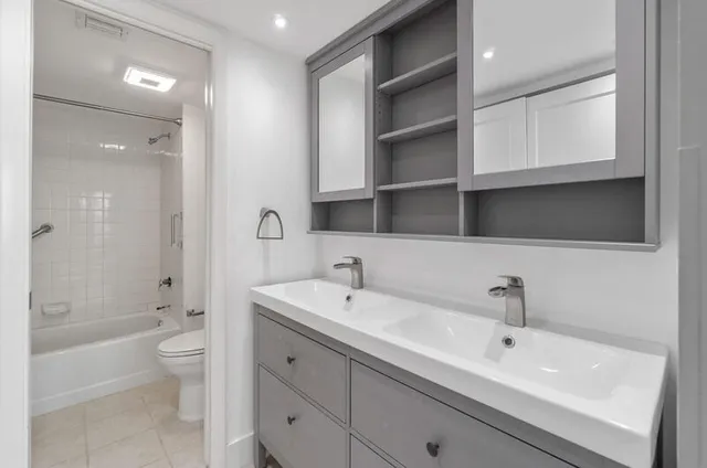 a bathroom with a bathtub shower sink vanity and toilet