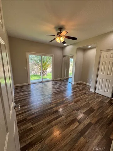 a view of an empty room with window and wooden floor