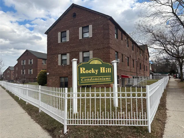 a view of a brick house with large windows and a gate