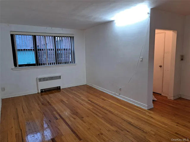 a view of an empty room with window and wooden floor