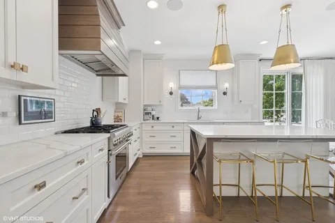 a kitchen with stainless steel appliances granite countertop a stove a sink dishwasher and white cabinets with wooden floor