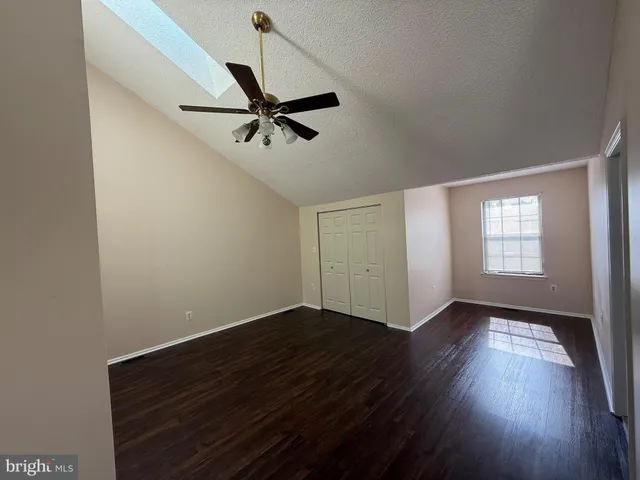 an empty room with wooden floor fan and windows