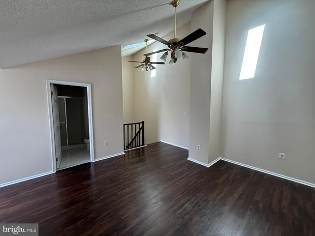 an empty room with wooden floor closet and windows