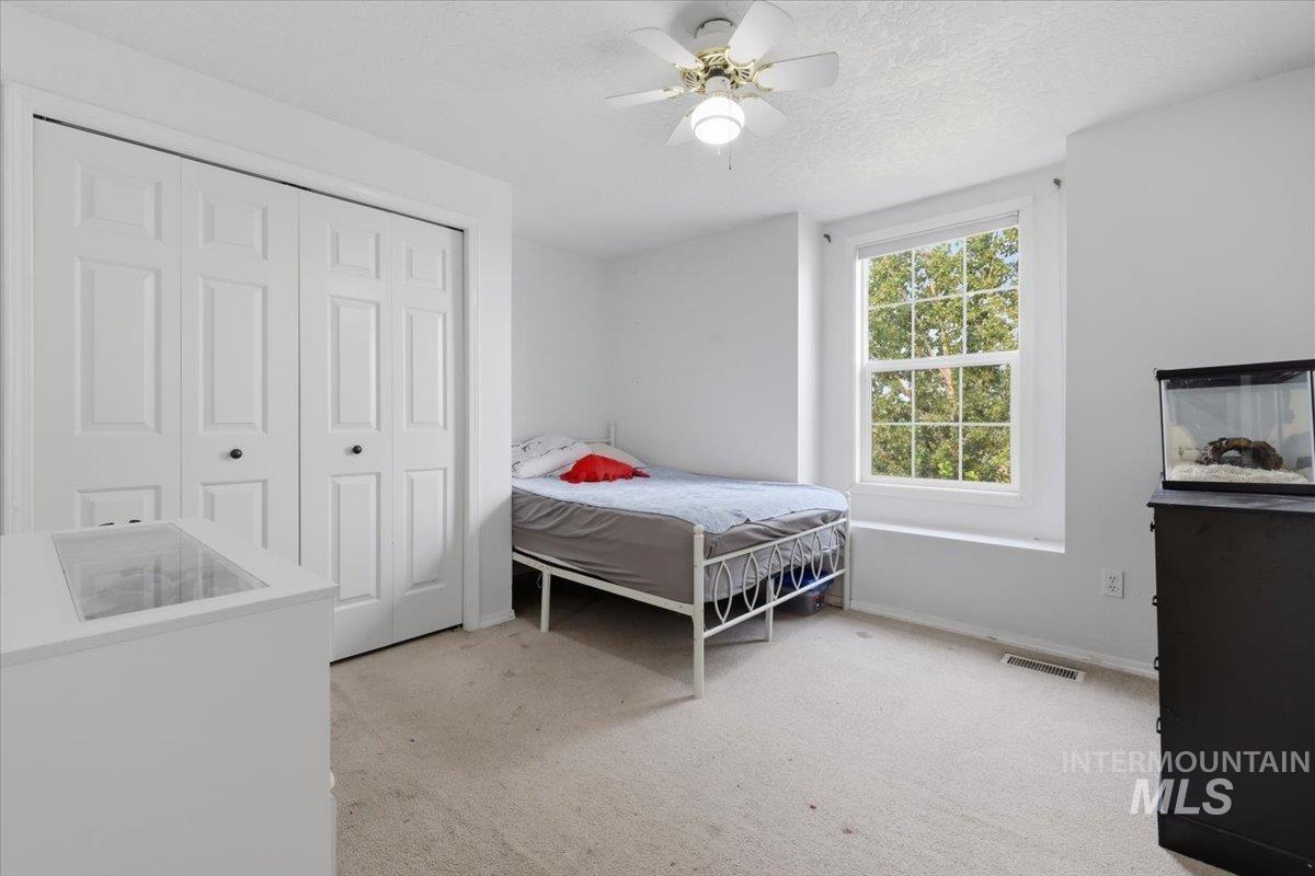 24440 Kenridge Road Caldwell, ID 83607 - Photo 39 of 48 Carpeted room featuring a double-door closet, a ceiling fan with integrated lighting, and a large window providing outdoor scenery