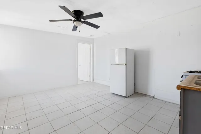 a view of an empty room and chandelier fan