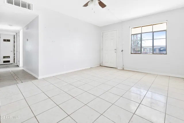 an empty room with windows and chandelier fan