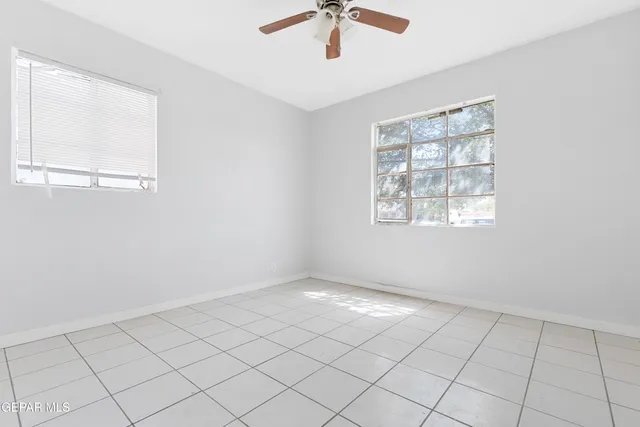 an empty room with windows and fan