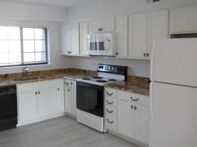 a kitchen with granite countertop white cabinets and white appliances