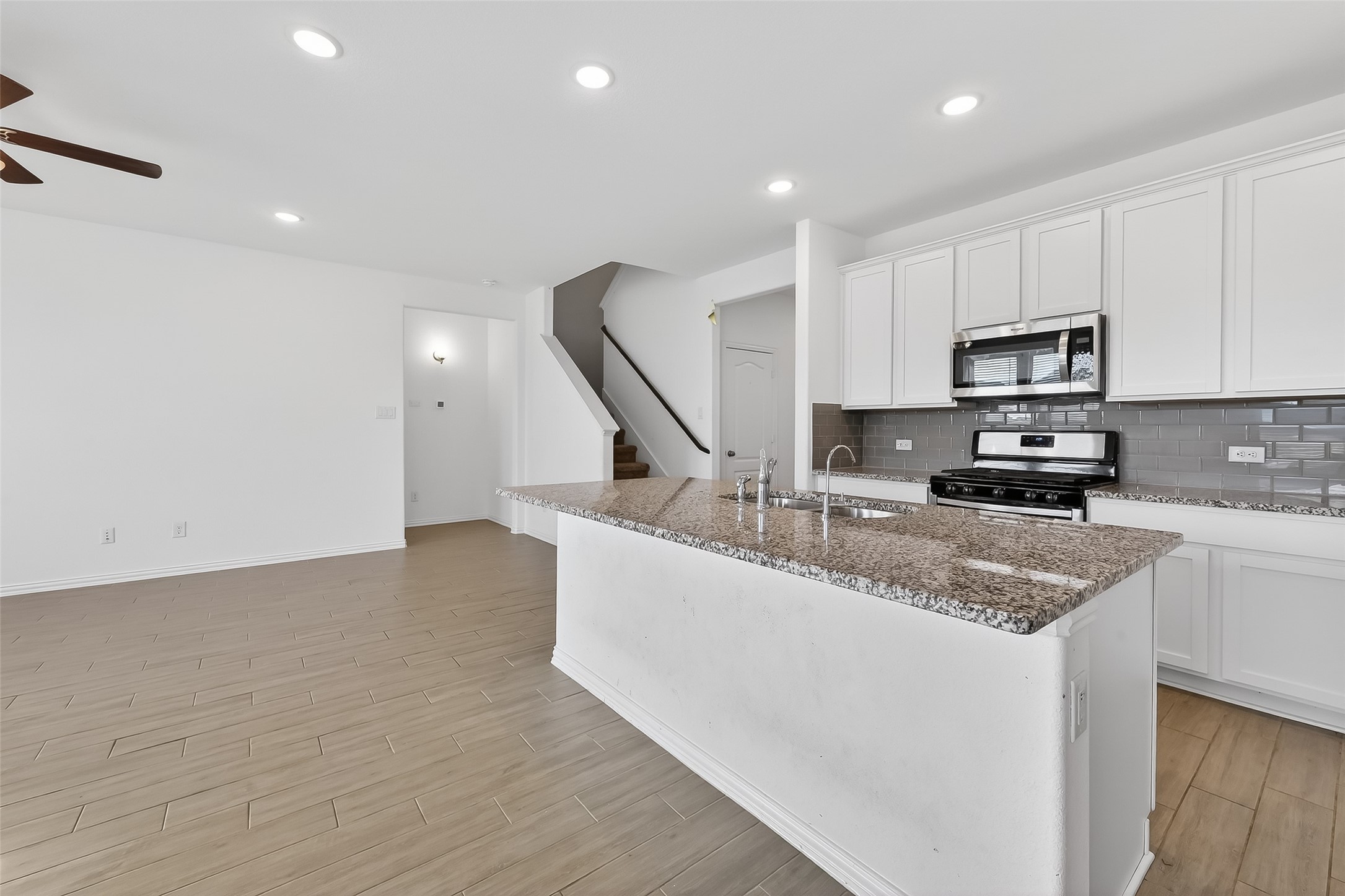 31215 Conover Drive Fulshear, TX 77441 - Photo 19 of 42 a kitchen with stainless steel appliances granite countertop a sink a stove and a microwave with wooden floor