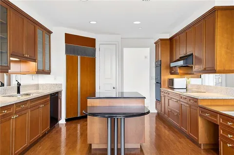 a kitchen with stainless steel appliances granite countertop a sink a stove a refrigerator cabinets and wooden floor