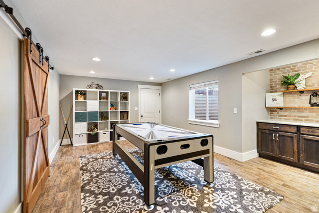 580 Cherry Ridge Lane Richmond, UT 84333 - Photo 36 of 53 Recreation room featuring a barn door, light wood-style flooring, and recessed lighting