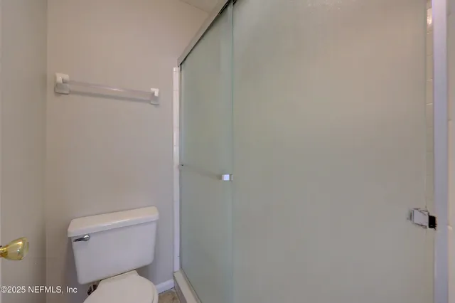 a white toilet sitting next to a shower