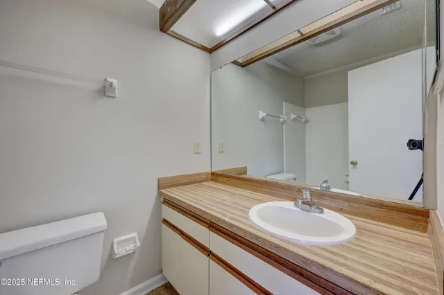 a bathroom with a granite countertop sink a toilet and a mirror