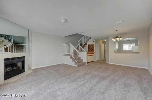 a view of an empty room with chandelier and fireplace