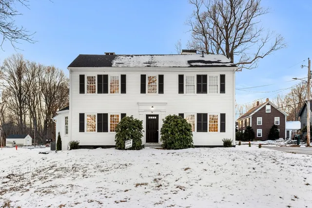a view of a white house with a yard covered in snow