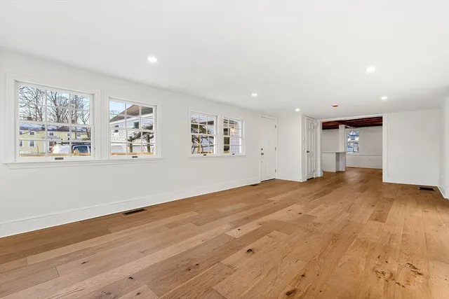 a view of empty room with wooden floor and window