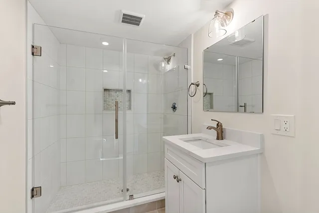 a bathroom with a shower sink vanity and mirror