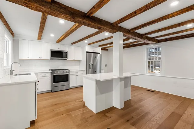 a kitchen with kitchen island granite countertop a stove top oven a sink dishwasher a dining table and chairs with wooden floor