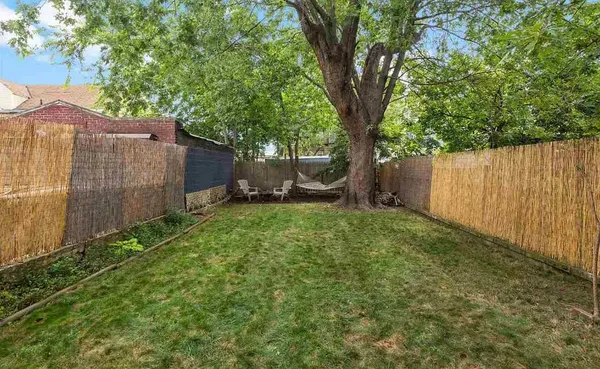 a view of a backyard with large trees and wooden fence