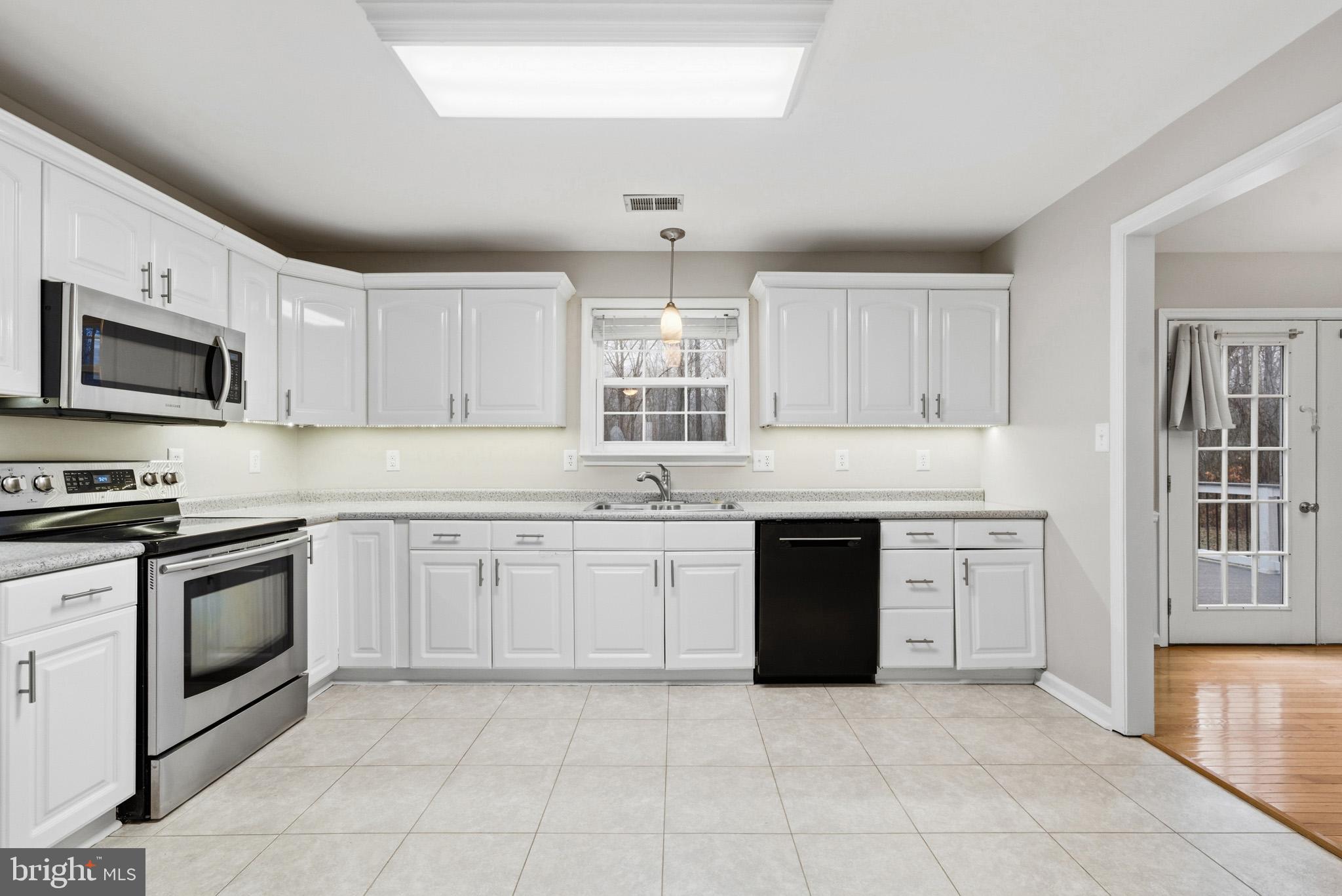 22343 Newtowne Neck Road Leonardtown, MD 20650 - Photo 11 of 40 a kitchen with granite countertop a stove sink and microwave