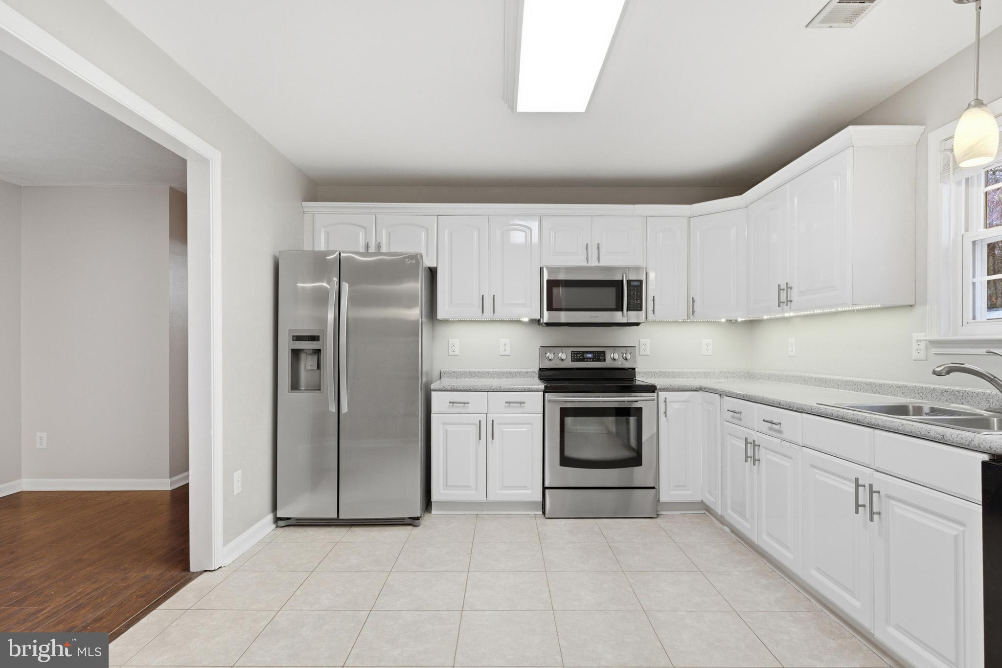 22343 Newtowne Neck Road Leonardtown, MD 20650 - Photo 13 of 40 a kitchen with white cabinets and stainless steel appliances