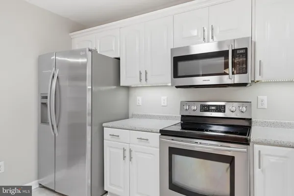 a kitchen with stainless steel appliances white cabinets white stove a microwave and a refrigerator