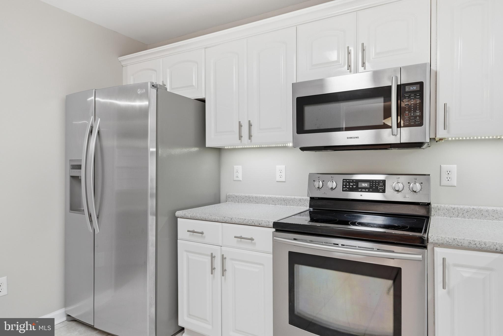 22343 Newtowne Neck Road Leonardtown, MD 20650 - Photo 16 of 40 a kitchen with stainless steel appliances white cabinets white stove a microwave and a refrigerator