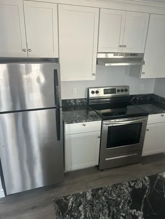 a kitchen with granite countertop a refrigerator stove and cabinets