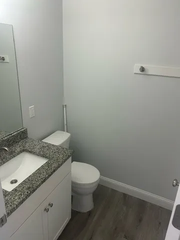 a bathroom with a granite countertop sink toilet and a mirror