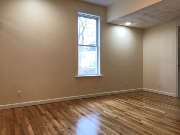 141 Jefferson Avenue, Unit 2 Everett, MA 02149 - Photo 4 of 10 an empty room with wooden floor and windows