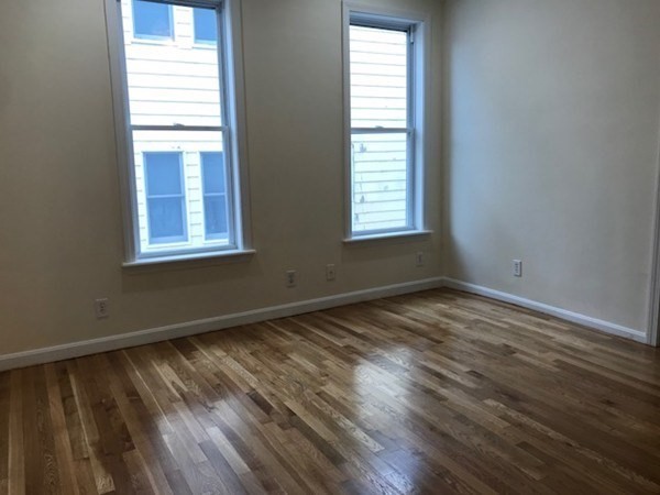 141 Jefferson Avenue, Unit 2 Everett, MA 02149 - Photo 7 of 10 an empty room with wooden floor and windows