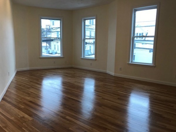 141 Jefferson Avenue, Unit 2 Everett, MA 02149 - Photo 8 of 10 an empty room with wooden floor and windows