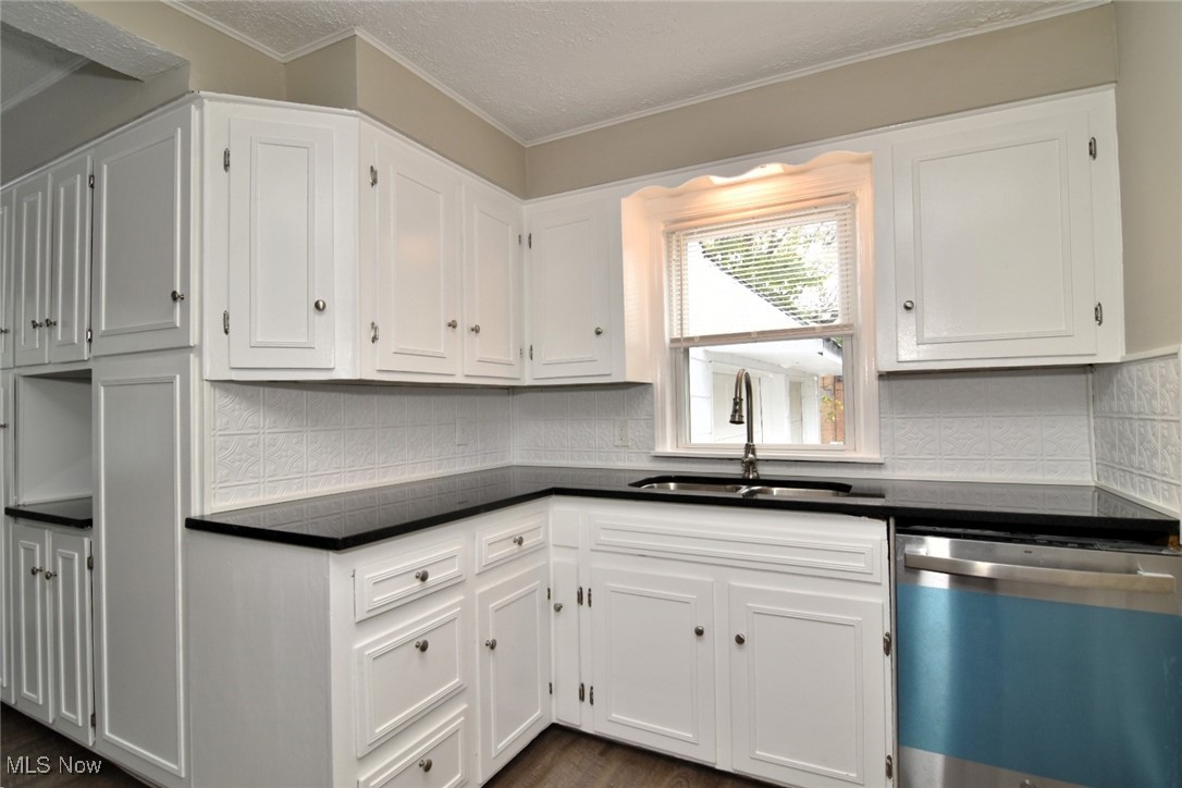 1443 Churchill Road Lyndhurst, OH 44124 - Photo 20 of 39 Kitchen featuring stainless steel dishwasher, dark countertops, white cabinetry, crown molding, and a textured ceiling