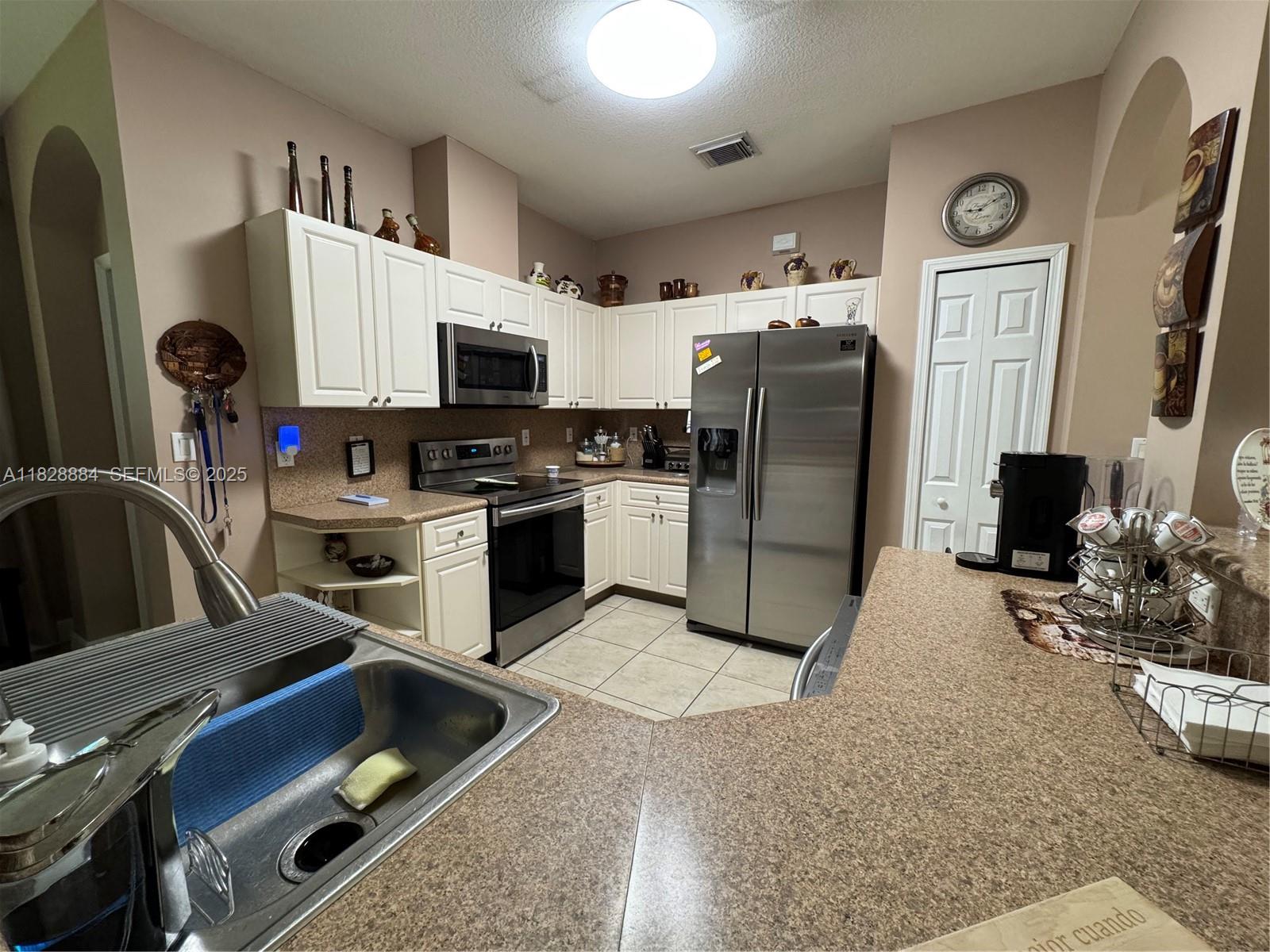 20233 Southwest 128th Place Miami, FL 33177 - Photo 11 of 21 a kitchen with stainless steel appliances granite countertop a refrigerator a stove a sink dishwasher a dining table and chairs with wooden floor